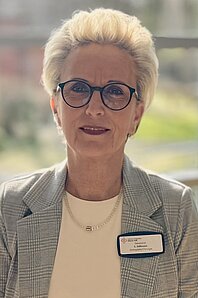 Porträt von Claudia Süßman, einer Frau mittlerenAlter smit blonden Kurzhaarschnitt und Brille, die als Sekretärin der Orthopädie im Cellitinnen-Krankenhaus Maria-Hilf in Bergheim arbeitet