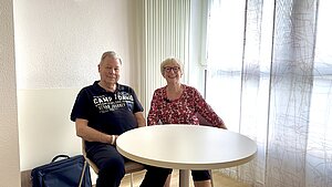 Herr und Frau Strick an einem runden Tisch am Fenster ihres Krankenhauszimmers