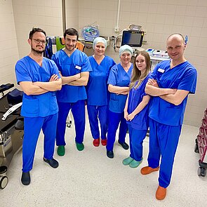 Drei Ärzte und drei Frauen in blauer OP-Kleidung