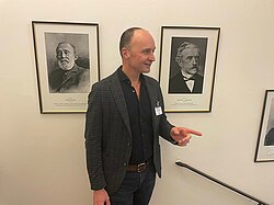 Dr. Hoeckle neben zwei schwarzweiß Porträts der Ärzte Bernhard von Langenbeck und Rudolf Virchow