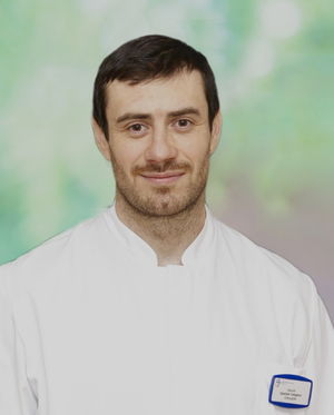 Porträt eines Arztes in weißem Kittel vor grünem Hintergrund