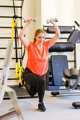 Junge Frau bei Sportübungen im Fitnessstudio